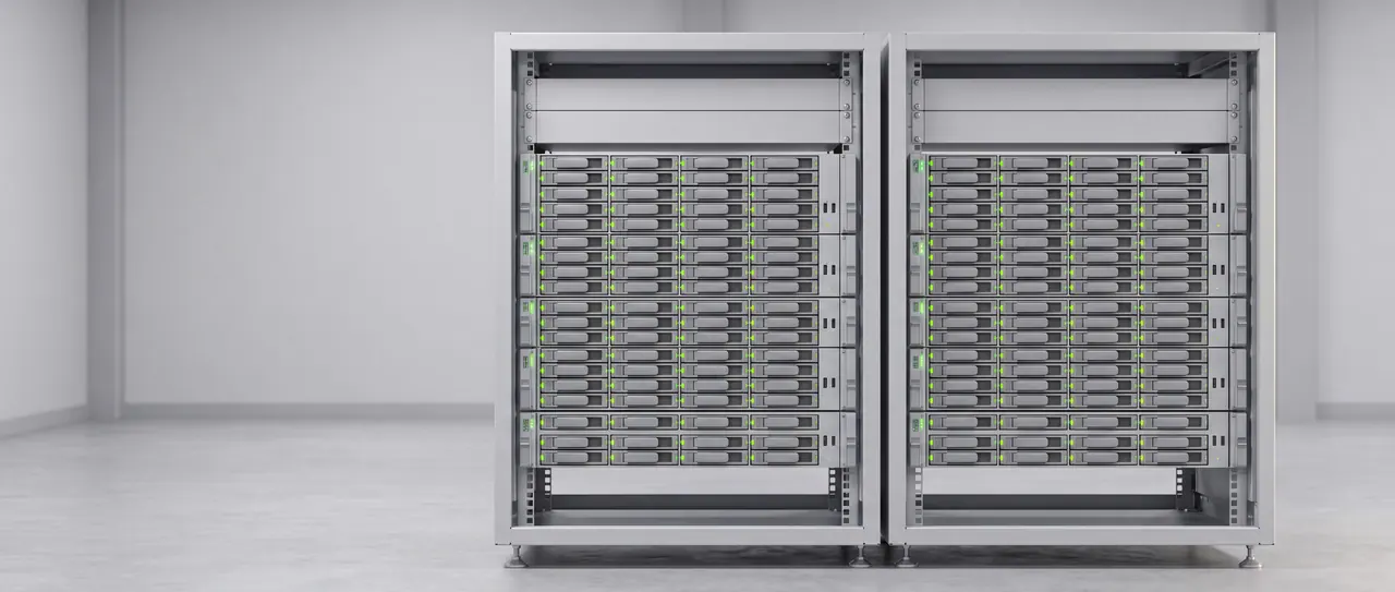 Zwei voll bestückte Serverschränke nebeneinander in einer hellen, leeren Halle, oben in jedem ein Switch; alle Statusleuchten der Server leuchten grün.